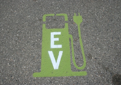 A painted sign on a street designating a spot to recharge a vehicle