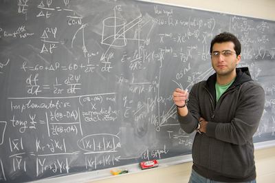 A student next to a chalkboard in the Syracuse University SmartLab.